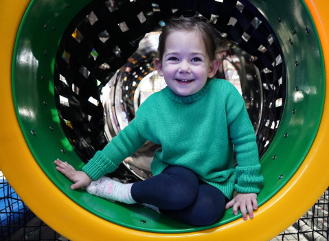 A toddler smiling on an indoor slide